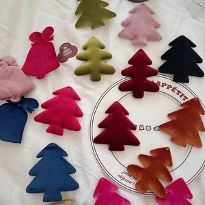 Detailed view of colorful velvet Christmas tree and bell hanging ornaments on a ceramic plate