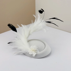 Detailed view of elegant white and black feathers with pearl flower on grey fascinator