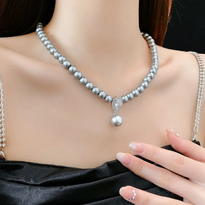 Detail of grey pearl necklace with zircon teardrop pendant worn on model neck
