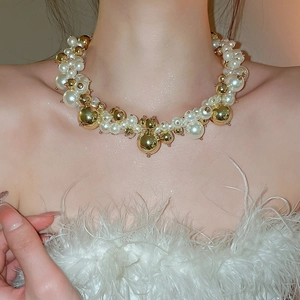 Detailed view of layered pearl and gold bead choker necklace on model with white feathers