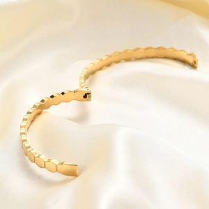 Detailed shot of hexagonal gold bangle with a wave edge and polished matte finish
