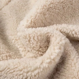Close-up macro detail of the soft cream white faux shearling fabric texture on a jacket