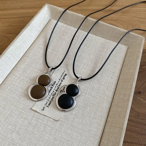 Detail of leather inlaid gourd pendants in brown and black on a minimalist fabric tray