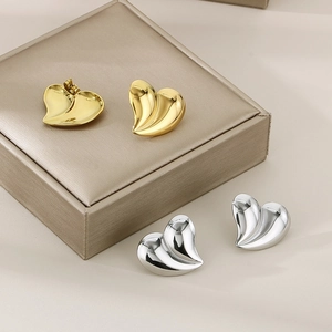 Macro view of irregular pleated heart studs in gold and silver finish on a jewelry box