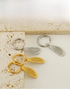 Detailed view of gold and silver hollow wing earrings on natural stone surface