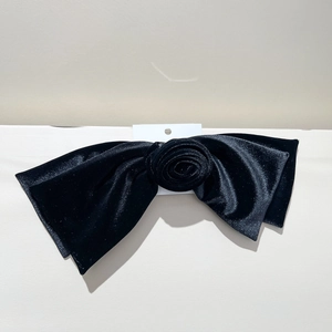 Détail d'une grande barrette en velours noir avec nœud de rose sur carte de présentation