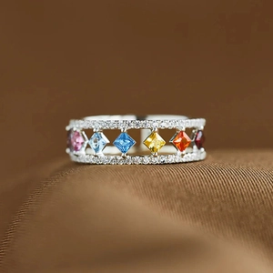 Detail van een geometrische zilveren ring met kleurrijke edelstenen op bruine zijde