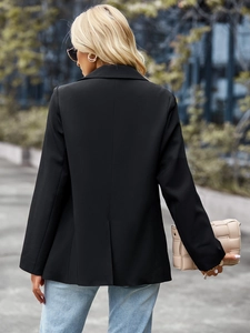 Detail of a black women's blazer featuring a sleek back slit and tailored mid-length cut