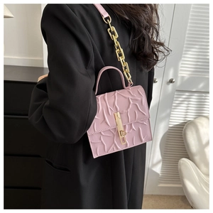 Pink chain crossbody bag with textured vine patterns shown on a model's shoulder