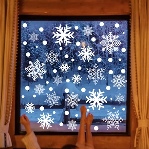 Close-up of white snowflake static window decals on a wooden frame with snowy background