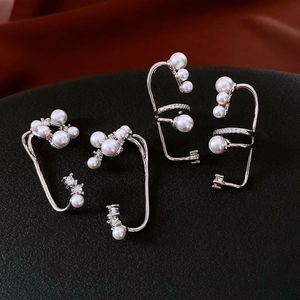 Detailed macro view of silver ear cuffs with clusters of white pearls and sparkling zircons