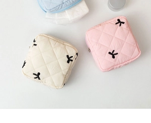 Detailed close-up of quilted sanitary napkin pouch with black bow embroidery and zipper