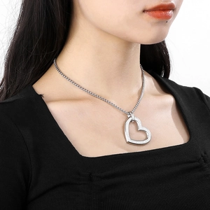 Detail of silver heart pendant with small diamonds worn on neck with clear texture