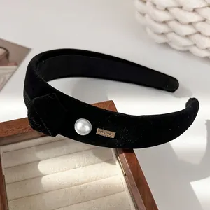 Detail of black velvet padded headband featuring a pearl and gold LOVEDAYS metal tag
