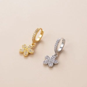 Close-up of gold and silver flower drop earrings featuring sparkling zircon crystal details