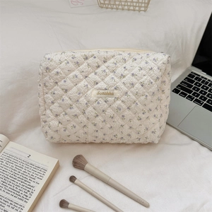 Detailed view of the quilted floral toiletry bag with zipper and logo tag on fabric