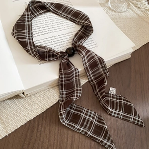 Macro detail of brown plaid chiffon scarf necklace with black ball bead ornament