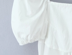 Détail rapproché des manches bouffantes blanches avec poignets élastiques et coutures