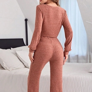 Women's dusty pink ribbed knit pajama set with long sleeves and pants in bedroom setting