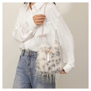 Detail of faux fur crossbody bag with black spots and elegant gold clasp closure
