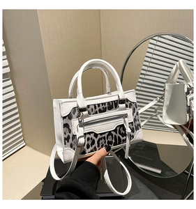 Detalle del bolso de leopardo con ribete de cuero blanco y detalles de cremallera