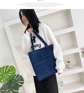 Dettaglio della borsa tote in denim blu scuro con doppie tasche anteriori e cuciture rinforzate