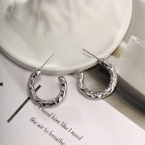 Detail of silver C-shape earrings with molten lava texture and stainless steel posts
