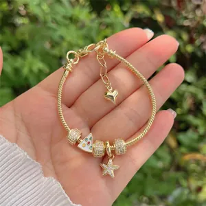 Detail of 18K gold-plated snake chain bracelet with sparkling star and heart charms