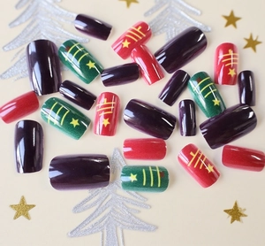 Detail of square-oval Christmas press-on nails in red, green, and purple with star motifs