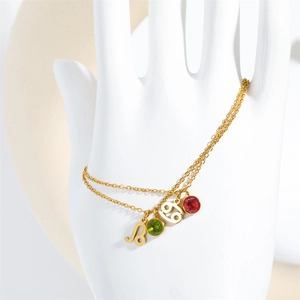 Close-up of golden double-layer bracelet with Leo and Cancer zodiac charms and gemstones