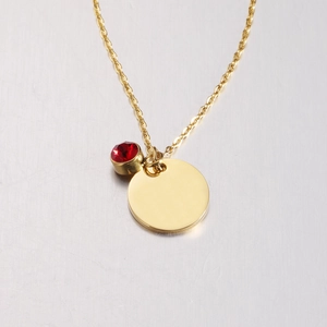 Polished gold round pendant necklace with red crystal charm in minimalist style