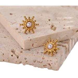 Vintage gold stainless steel sunburst earrings with pearl inlay on stone background