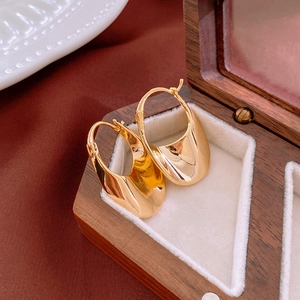 Macro shot of wide curved gold hoop earrings with mirror polished finish in a jewelry box
