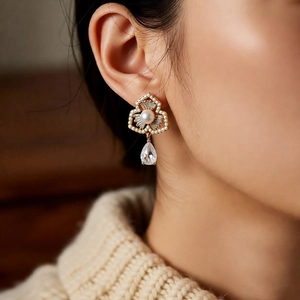 Close-up of a vintage gold flower earring with a white pearl and teardrop crystal charm