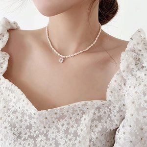 Baroque rice pearl necklace with a square clear crystal pendant worn on neck