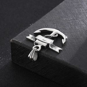 Macro shot of silver pirate anchor pendant with detailed rope and banner on black surface
