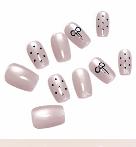 Detail of cat-eye nails with black polka dots and pearl-decorated bow accents