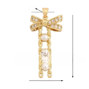 Détail d'un pendentif nœud doré avec zircons incrustés et perles d'imitation suspendues