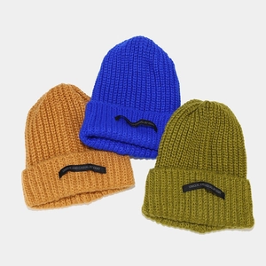 Detalle de gorros de punto grueso en amarillo mostaza, azul real y verde oliva con etiqueta