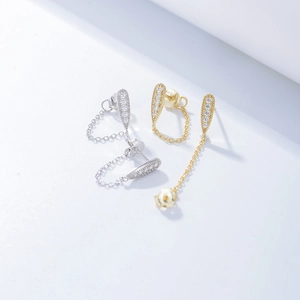 Detail of drop-shaped zircon earrings with chain tassels in gold and silver finish