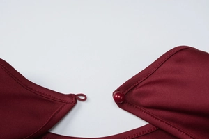 Dettaglio dello scollo dell'abito rosso vino con eleganti bottoni di perle abbinati