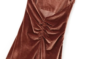 Detailed close-up of ruched velvet texture and pleated fabric on a caramel midi dress