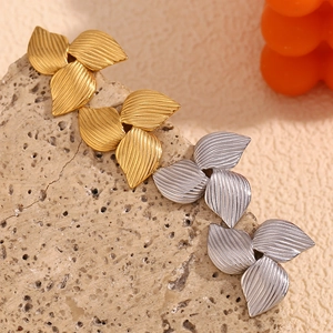 Macro detail of boomerang leaf earrings in 18K gold and silver plating on rock