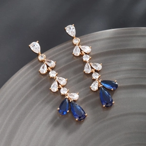 Macro detail of luxury teardrop blue zircon tassels on gold plated dangling earrings
