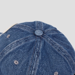 Macro view of the washed denim baseball cap crown showing stitch lines and eyelets