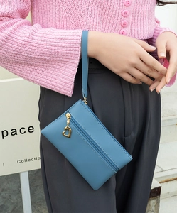 Close-up of blue PU leather wristlet with gold heart zipper pull and wrist strap