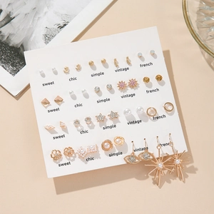 Flat lay detail of a 20-pair gold earring set with heart and pearl designs on display card