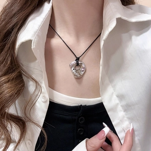 Detail view of a silver irregular geometric ring pendant on a black cord necklace