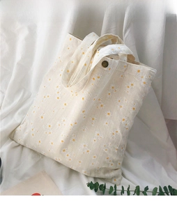 Detail of canvas tote bag with daisy print, featuring double straps and magnetic closure