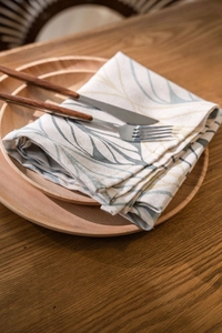 Close-up of cotton linen napkin with green leaf pattern on a wooden serving tray